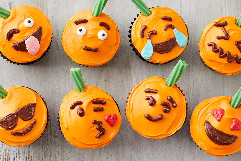 Cupcakes with orange frosting decorated as emojis