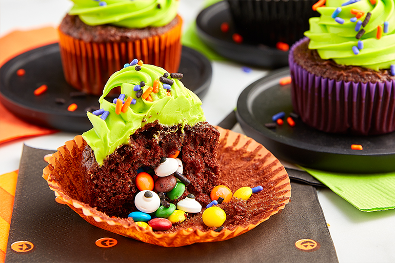 Chocolate cupcakes with green frosting filled with chocolate covered candy