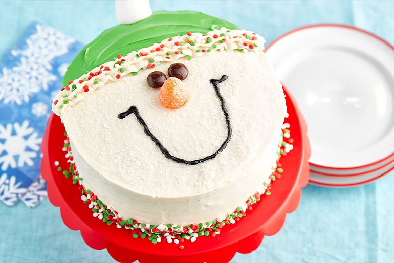 Cake decorated as a holiday snowman with a green hat