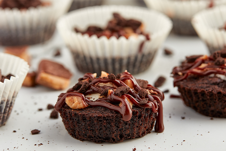 Small brownies drizzled with fudge chocolate and some pecans