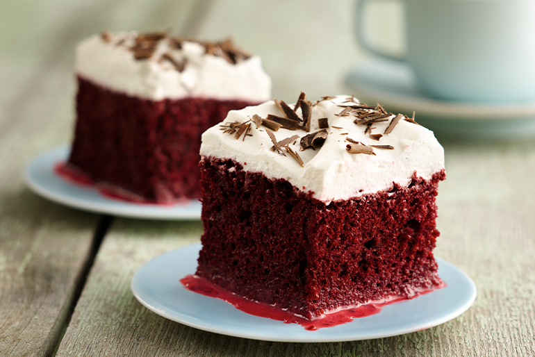 Pastel de red velvet tres leches con crema blanca encima y trozos de chocolate